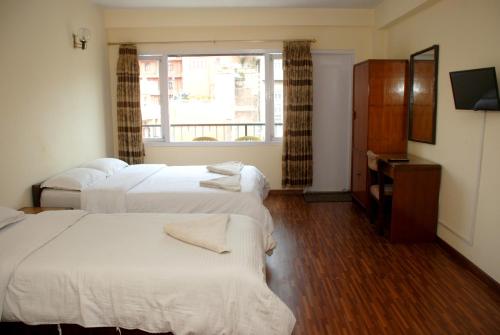 a hotel room with three beds and a window at Kathmandu Madhuban Guest House in Kathmandu