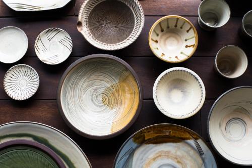 a group of bowls and plates on a wooden table at Yamada Bessou くつろぎの温泉宿 山田別荘 in Beppu