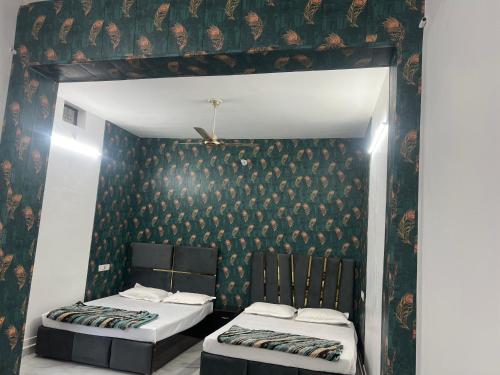 two beds in a room with a wall with wallpaper at Hotel Sankul Villa, 100 Meter Away Saryu River & Ram Ki Paidi, Lux Stay in Ayodhya