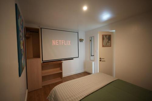 a large screen in a room with a bed at Le Ptit Kozhi, Confort, Nature & Plages in Plouay