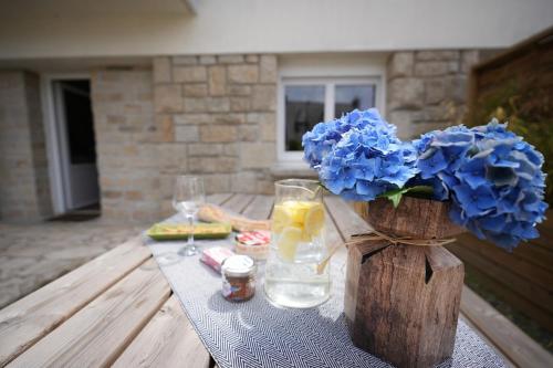 a table with a vase of blue flowers and drinks at Le Ptit Kozhi, Confort, Nature & Plages in Plouay