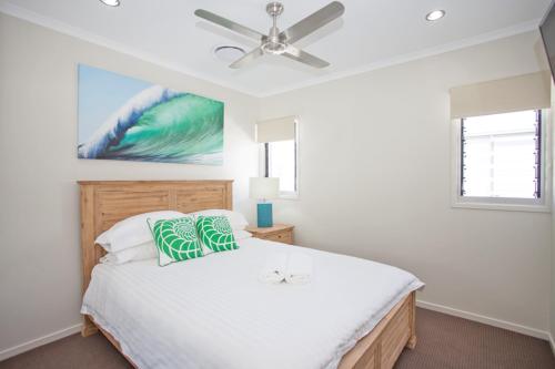 a bedroom with a white bed with a ceiling fan at Petrie Beach Holiday Home in Mackay