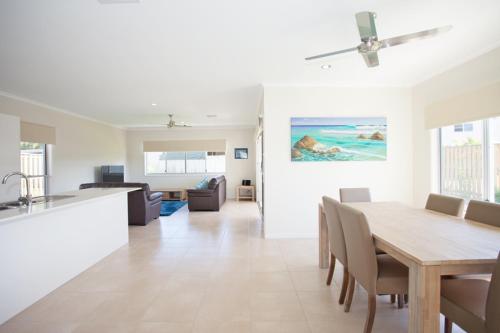 a dining room and living room with a table and chairs at Petrie Beach Holiday Home in Mackay