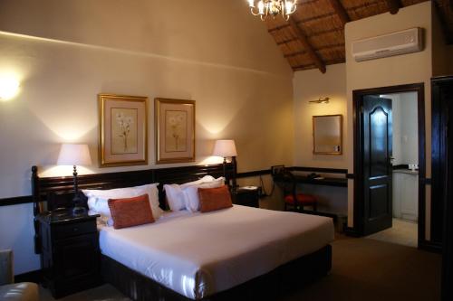 a bedroom with a large bed and a desk at Kievits Kroon Gauteng Wine Estate in Pretoria