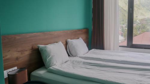 a bed with white sheets and pillows next to a window at Shushabandi Kazbegi in Stepantsminda