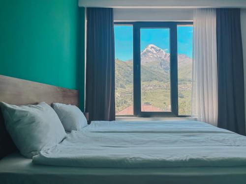 a bedroom with a bed with a view of a mountain at Shushabandi Kazbegi in Stepantsminda