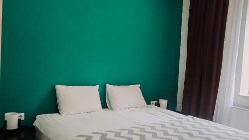 a bed with a green wall and two pillows at Shushabandi Kazbegi in Stepantsminda