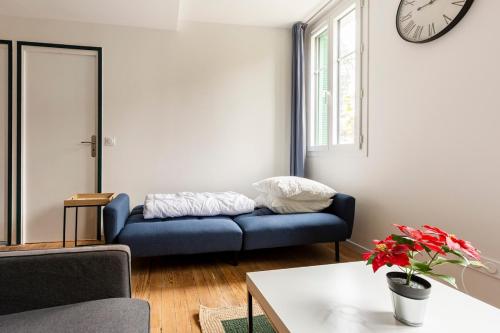 - un salon avec un canapé bleu et une horloge murale dans l'établissement T2 Cosy proche Gare et Centre Ville - Parking Gratuit à proximité, à Lourdes