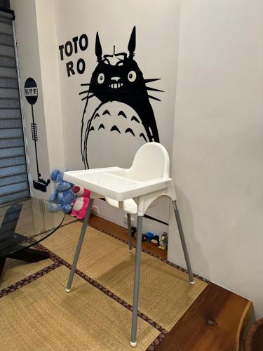 a white chair in front of a wall with a cat painted on it at 榛品包棟民宿 in Puli