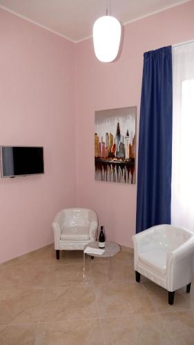 a living room with two white chairs and a tv at Cairoli Exclusive Rooms & Suite in Brindisi