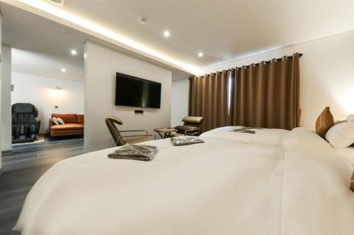 a hotel room with two white beds and a flat screen tv at Cheongju Maryjane Hotel in Cheongju