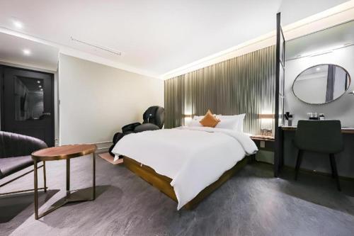 a bedroom with a bed and a desk and a mirror at Cheongju Maryjane Hotel in Cheongju