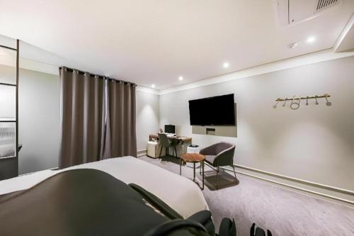 a hotel room with a bed and a desk and a tv at Cheongju Maryjane Hotel in Cheongju
