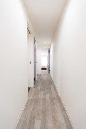 an empty hallway with white walls and wood floors at b&岸里店 in Osaka