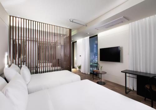 a bedroom with two beds and a desk and a television at Park Marine Hotel in Incheon