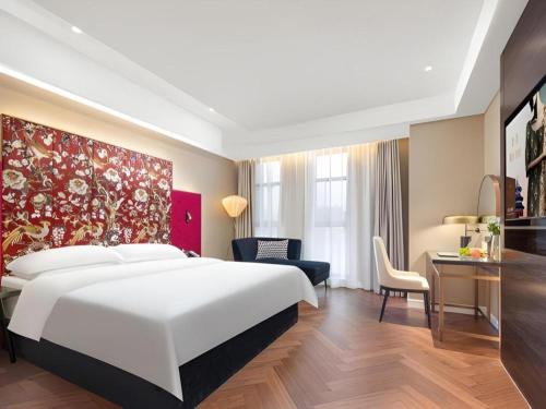 a bedroom with a large white bed and a desk at Jinjiang Metropolo Hotel - Taizhou Wanda Plaza in Taizhou