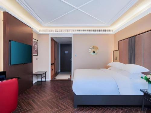 a bedroom with a large white bed and a desk at Jinjiang Metropolo Hotel - Taizhou Wanda Plaza in Taizhou