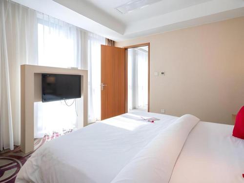 a bedroom with a white bed with a tv on it at Jinjiang Metropolo Hotel - Taizhou Wanda Plaza in Taizhou