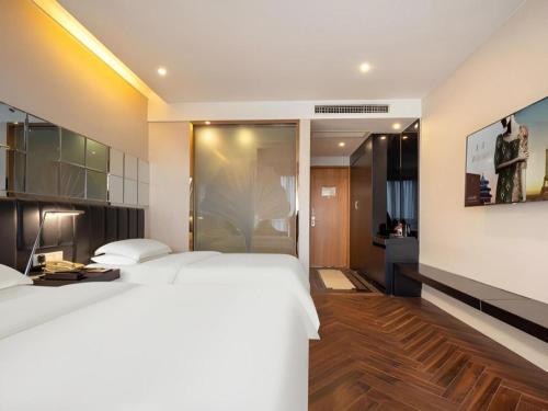 a bedroom with a large white bed and a bathroom at Jinjiang Metropolo Hotel - Taizhou Wanda Plaza in Taizhou