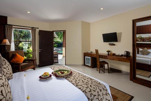 a room with a bed and a desk and a television at Kadiga Villas Ubud by GenuineHost in Ubud