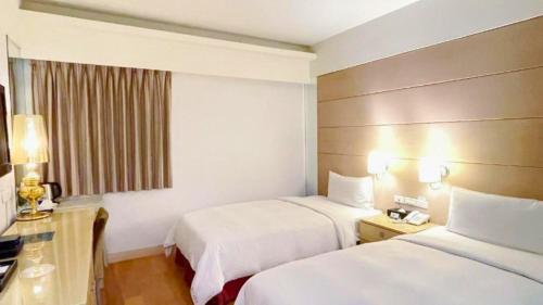 a hotel room with two beds and a desk at Delton Hotel in Kaohsiung