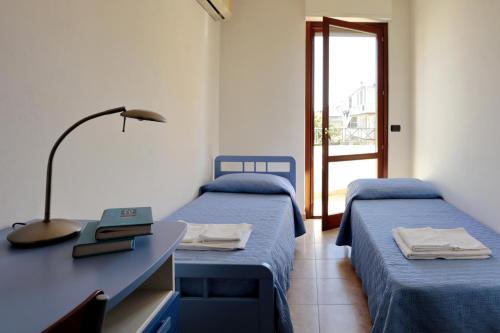 アルゲーロにあるMare Di Stelle casa vacanzeのベッド2台、デスク、窓が備わる客室です。