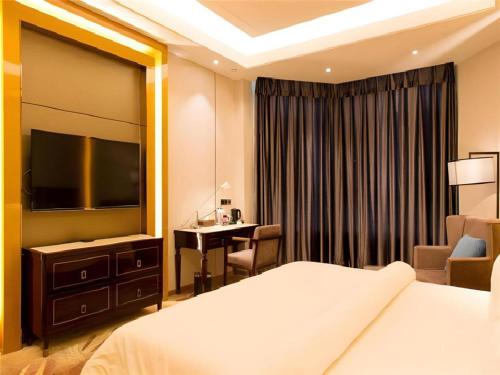 a hotel room with a bed and a desk and a television at Metropolo Hotel Yining Development Zone Hanma Building in Kipekyüzi