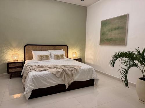 a bedroom with a bed with two lamps and a plant at Villa Kuu - Elegant 2BR Villa with Private Pool in Kerobokan