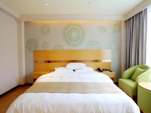 a bedroom with a large bed and a green chair at GreenTree Inn Tibet Nyingchi City Biji Shenshan in Nyingchi