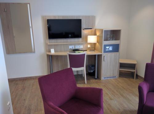 a room with a desk and a tv and two chairs at Hotel Zur-Borke in Neuenrade