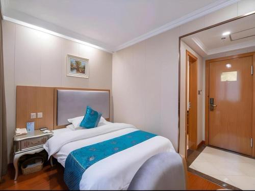 a bedroom with a large bed with a blue pillow at GreenTree Inn Wuxi Xinwu District Meicun Town Taibo Avenue in Wuxi