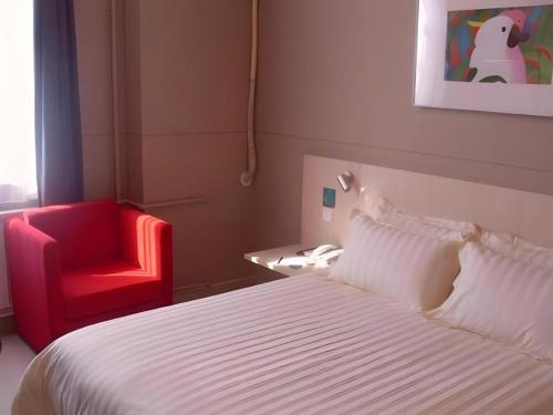 a bedroom with a bed and a red chair at Jinjiang Inn Qingdao Wuxi Square Nanjing Road Metro Station in Qingdao