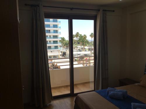 ein Schlafzimmer mit einem Fenster mit Blick auf einen Balkon in der Unterkunft Ithaki Phinikoudes Apartment No. 205 in Larnaka