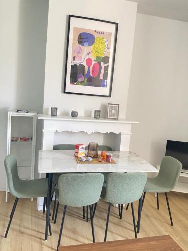 une table à manger avec des chaises et une photo sur le mur dans l'établissement Appt 6 couchages Jardin Parking laverie, à Dunkerque