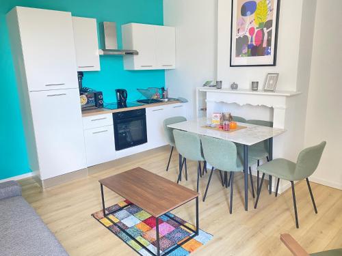 une cuisine avec une table et des chaises dans une pièce dans l'établissement Appt 6 couchages Jardin Parking laverie, à Dunkerque