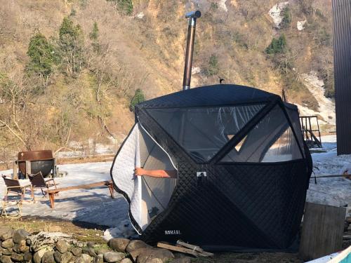 a black tent sitting on the ground in the snow at わくわく自然体験の宿ゲストハウス山楽 in Itoigawa