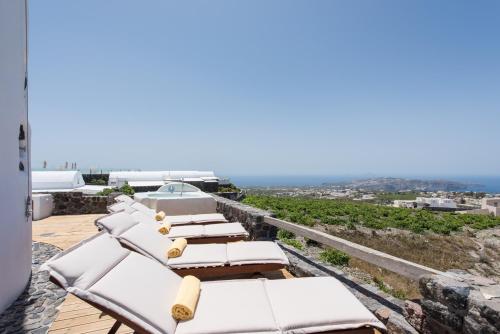 a group of lounge chairs on a balcony with the ocean at Anemoscope Windmill Villa in Pirgos