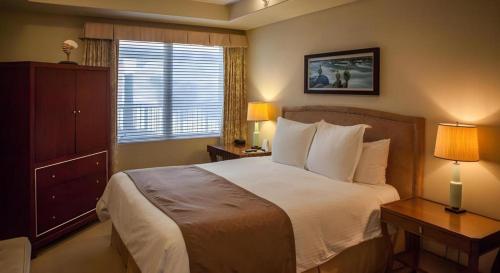 a bedroom with a bed with two lamps and a window at Dolphin Bay Resort and Spa in Pismo Beach
