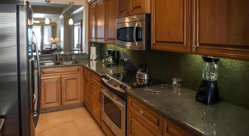 a kitchen with wooden cabinets and a stainless steel refrigerator at Dolphin Bay Resort and Spa in Pismo Beach
