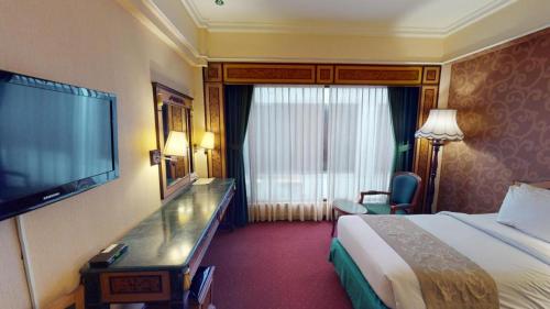 a hotel room with a bed and a flat screen tv at Gajahmada Graha Hotel in Malang