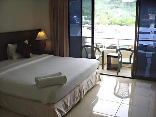 une chambre avec un grand lit blanc et un balcon dans l'établissement Kamala Phuyai Resort, à Kamala Beach