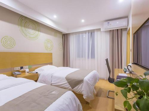 a hotel room with two beds and a television at GreenTree Inn Xuzhou Ruojia Express Hotel in Xuzhou