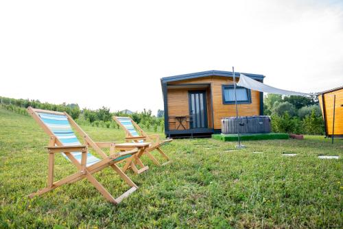 two deck chairs sitting in the grass in front of a tiny house at Seosko Domaćinstvo Protic , Prijedor , Veliko Palančište in Velika Palančište