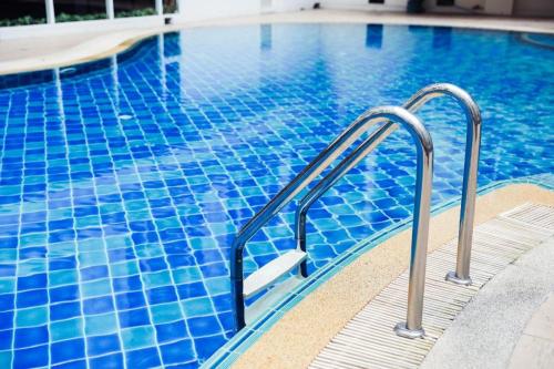 a blue swimming pool with a stairway leading into the water at Thaisun Bangkok Hotel in Bangkok