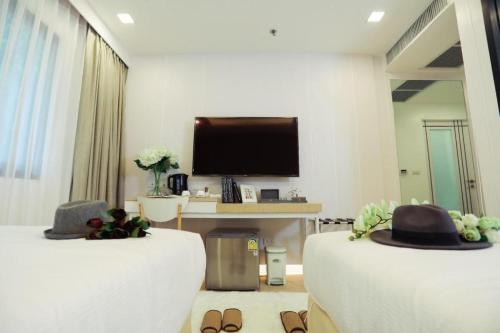 a living room with two beds and a flat screen tv at Thaisun Bangkok Hotel in Bangkok