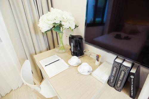 a table with a vase of white flowers on it at Thaisun Bangkok Hotel in Bangkok