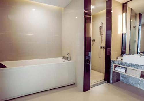 a bathroom with a tub and a sink at Echarm Hotel Qionghai Wanquan River in Qionghai