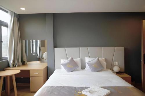 a bedroom with a large bed with white sheets and pillows at Gold View Boutique Hotel Đà Lạt in Da Lat