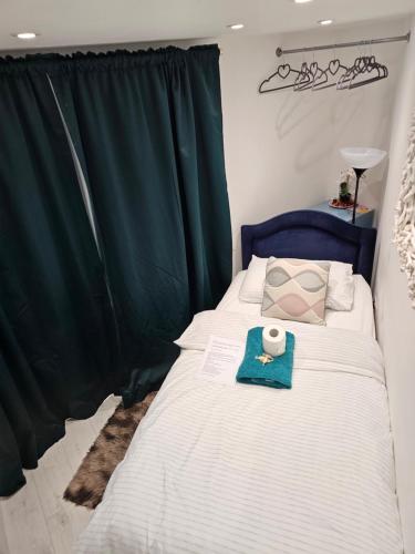 1 dormitorio con cama blanca y cortina verde en Single Cosy Bedroom in Dartford- Private Entrance for guest, en Kent