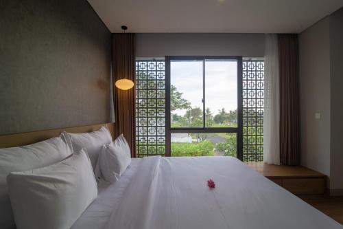 Un dormitorio con una cama blanca con una flor roja encima. en Villa Darmadi, en Tanah Lot